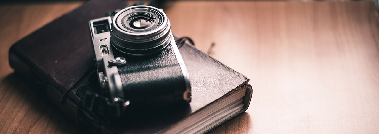 Vintage style camera on leather notebook on tabletop.