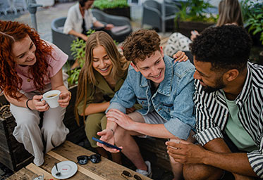 Friends sitting together drinking coffee at outdoor table.