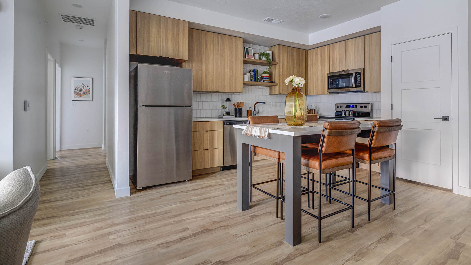 Kitchen with wood style floor and cabinets, light counters, and stainless steel appliances.